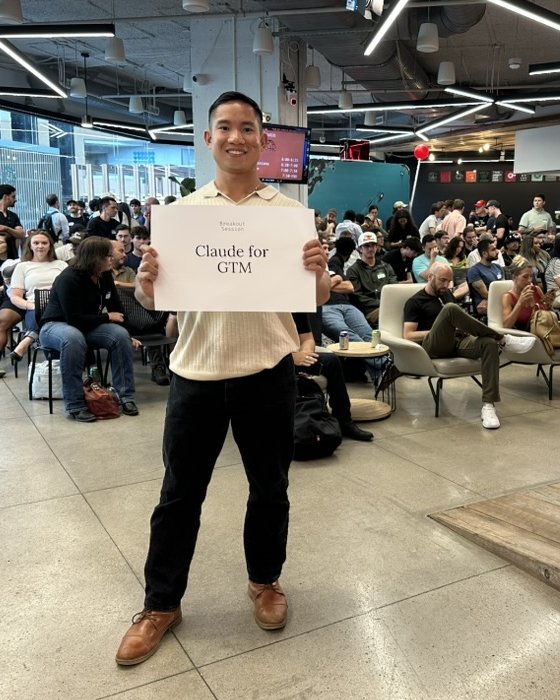 Facilitator holding a Claude for GTM breakout session sign at a packed event