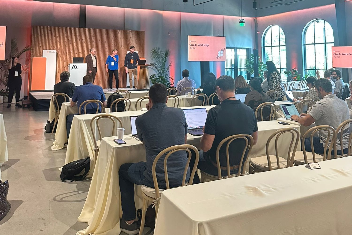 Attendees working on laptops at long tables during a Claude workshop in Austin