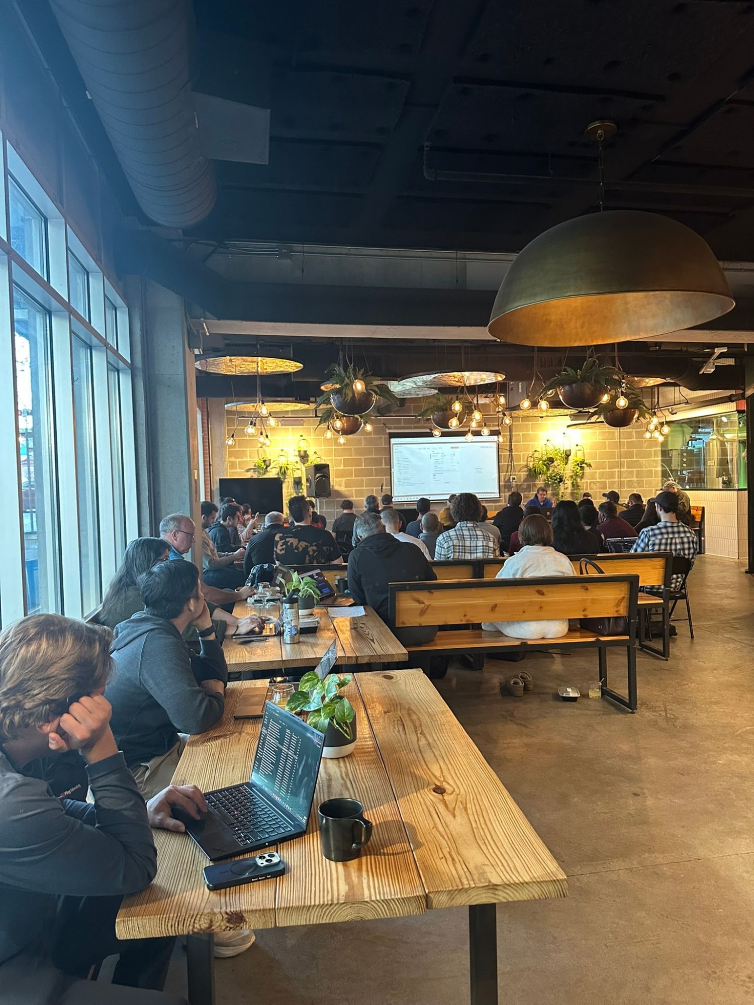 Participants with laptops at long tables during a hands-on AI build session